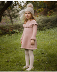 Pink knitted dress with a fluffy pink pom-pom.