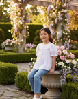 7-year-old Asian girl in white polka dot blouse with light blue jeans
