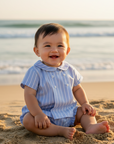 Asian baby boy in blue striped set smiling at the beach