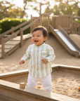 Asian baby boy in green striped shirt outdoor play area
