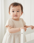 Asian baby girl in cream and white dress with white wooden background