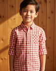 Asian boy in red gingham check shirt with wooden background
