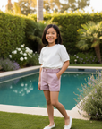 Asian girl 8 years old in pink shorts with white blouse by pool