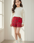 Asian girl in red tweed shorts indoors with white wooden background