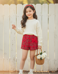Asian girl in red tweed shorts outdoors with white wooden background