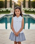 Asian girl in white polo dress with navy striped skirt in backyard with pool