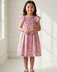 Lifestyle photo of 7-year-old Asian girl wearing pink floral dress with white wooden background
