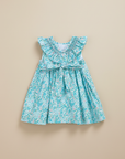 Product photo of turquoise floral dress with bow on beige background