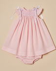 Professional product photo of smocked pink dress on beige background