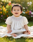 Realistic lifestyle photo of Asian baby girl wearing smocked dress outdoors
