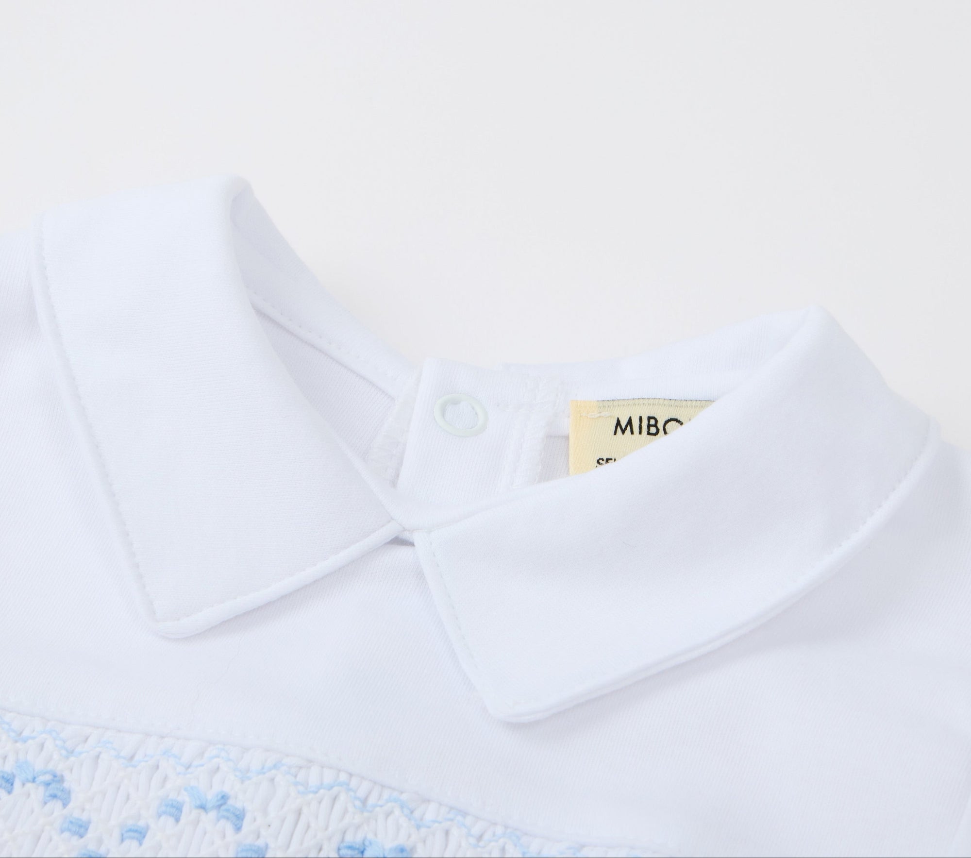 White polo shirt with blue embroidery on a white background