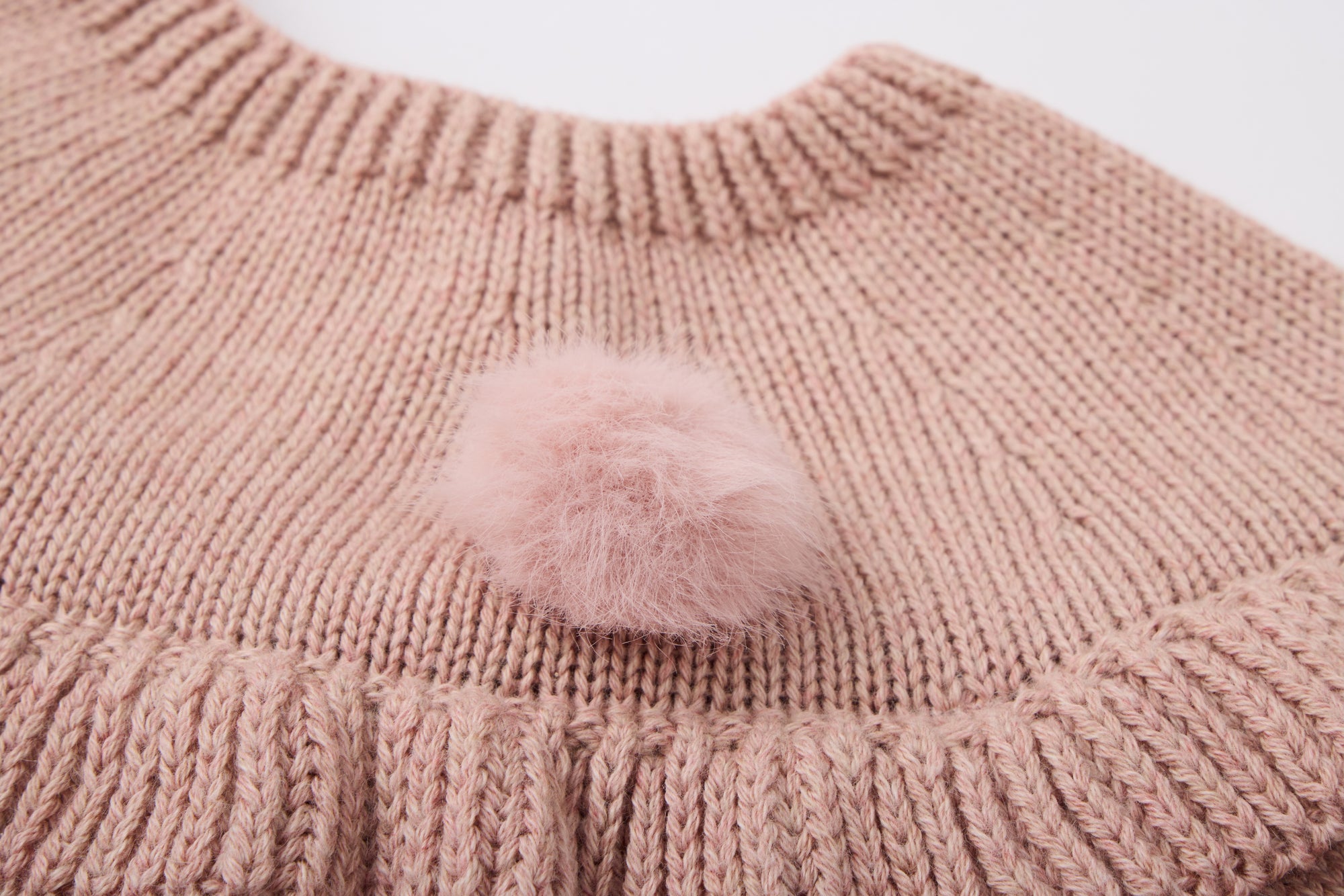 Pink knitted dress with a fluffy pink pom-pom.