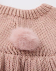 Pink knitted dress with a fluffy pink pom-pom.