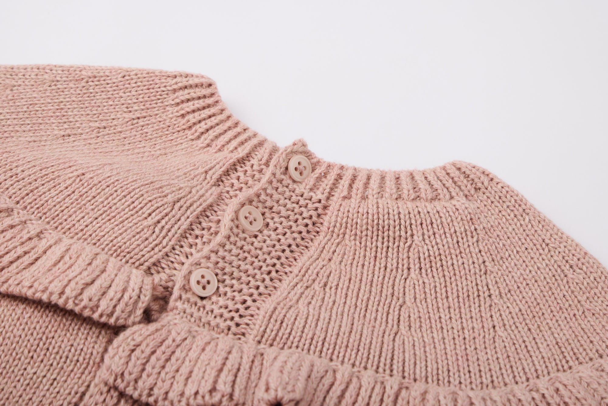 Pink knitted dress with a fluffy pink pom-pom.