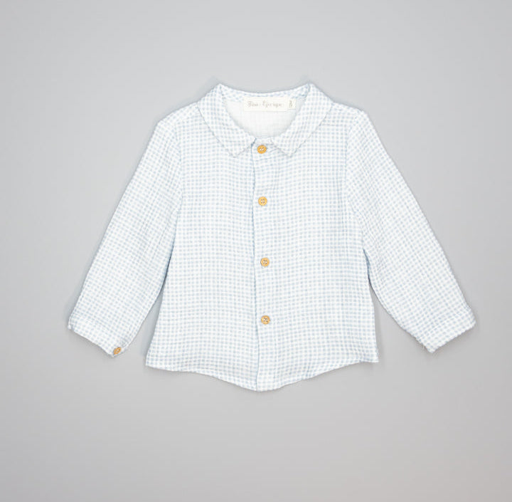 A light blue and white gingham long-sleeve button-up shirt for toddlers, featuring a Peter Pan collar and gold buttons, laid flat on a neutral gray background.