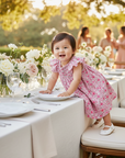 Asian baby girl in pink floral dress at garden celebration