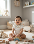 Asian baby girl in white knit romper in playroom