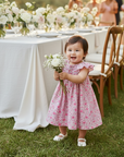 Asian baby girl standing with flower bouquet at garden celebration
