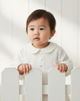 Asian baby in white peter pan collar blouse with white wooden background