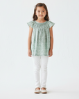 Asian girl in sage green smocked blouse with white jeans