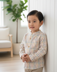 Asian little boy in multicolor plaid shirt with white wood background