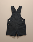 Dark navy denim dungaree shorts flat lay beige background