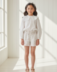 Lifestyle photo with Asian girl wearing floral shorts, white blouse and elegant flat shoes