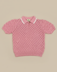 Pink knit polo sweater on beige background