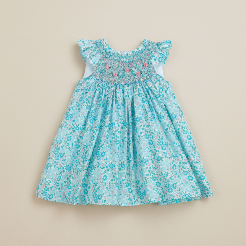 Product photo of turquoise floral smocked dress on beige background