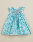 Product photo of turquoise floral smocked dress on beige background