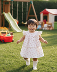 Realistic lifestyle photo of Asian baby girl wearing pink floral dress in kids play area