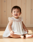 Realistic luxury lifestyle photo of Asian baby girl seated on floor with wooden beige background