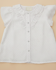 White star print blouse flat lay no logo beige background